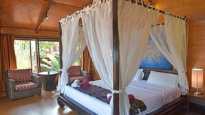 A four-poster canopy bed with a ceiling fan, a wicker armchair, and a nightstand with a lamp. - 3 bed beach front villa (Koh Samui)