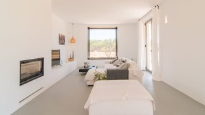 Un dormitorio moderno con un ventanal grande, una cama, un sofá y un televisor.