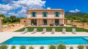 Una casa de dos pisos con piscina, mobiliario exterior y vistas del paisaje circundante.