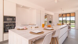 Una cocina moderna con una isla grande, electrodomésticos integrados y vistas al exterior.