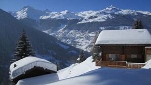 A wooden cabin with a snow-covered roof, surrounded by snow-covered mountains and trees. - Chalet Cuckoo, Romantic Alpine Getaway. Val d'Anniviers, Valais, Switzerland (Ayer)