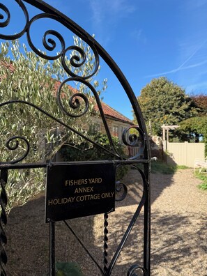 Um portão de metal com uma placa que diz 'FISHERS YARD ANNEX HOLIDAY COTTAGE ONLY'.