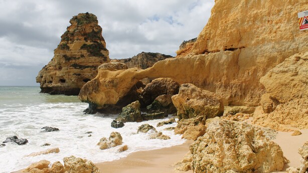 A coastal landscape with rocky formations and a sandy beach.