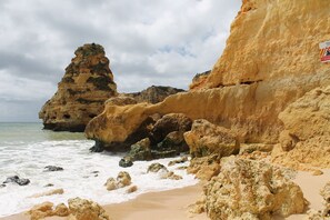 A coastal landscape with rocky formations and a sandy beach.