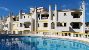 A large swimming pool with a white and yellow building in the background.
