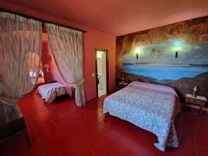 Una camera da letto con un letto grande, un letto più piccolo e un affresco raffigurante una spiaggia.