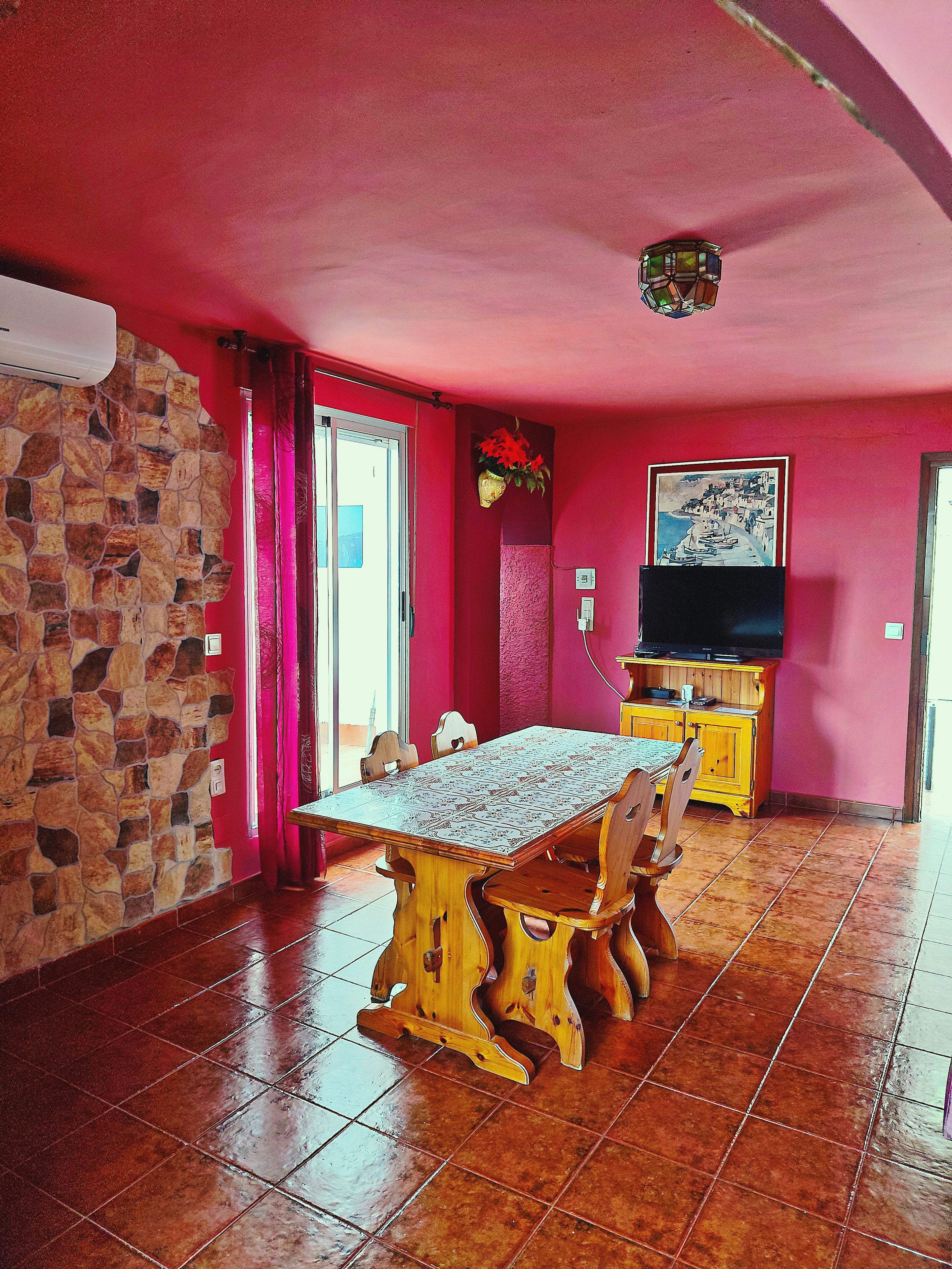 Uma sala de jantar com parede de pedra, mesa de madeira e cadeiras.