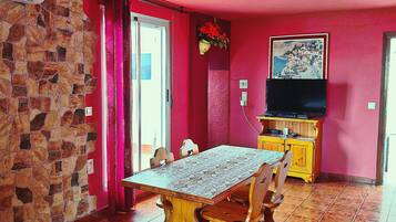 Uma sala de jantar com parede de pedra, mesa de madeira e cadeiras.