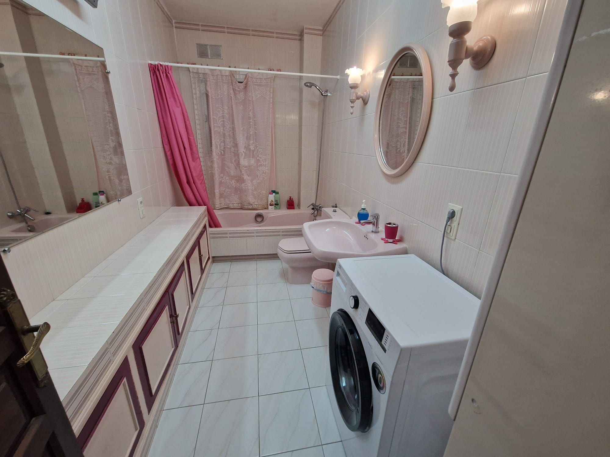 Casa de banho com banheira, sanita, lavatório e máquina de lavar roupa.