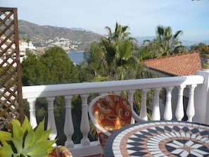 A balcony with a white balustrade, a patterned cushion, and a tiled floor.
