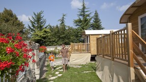 A wooden deck with a wooden railing, a stone wall with red flowers, and a clear sky.