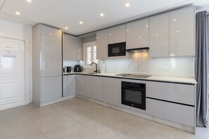 A modern kitchen with white cabinets, a black microwave, a built-in oven, and a dishwasher.