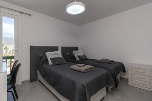 A bedroom with two beds, a desk, and a chair. - Sunset Bay 45 - Two Bed (Costa Adeje)