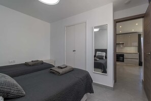 Un dormitorio con dos camas, un armario y un espejo que refleja otra habitación.