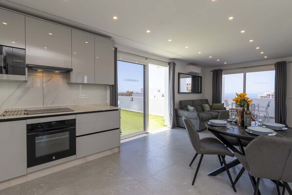A modern kitchen with a built-in oven and a dining area with a table set for two.