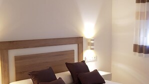 A neatly made bed with a wooden headboard, a bedside table, and a lamp. - MIRADORES DEL ISASA - VIURA-NEOSENS STUDIO APARTMENT (HERCE, La Rioja)