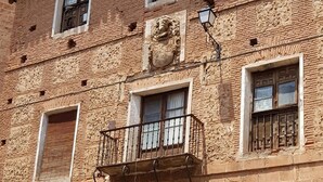 A historic building with a traditional facade, multiple windows, a central entrance with a metal gate, and a metal bench in front. - MIRADORES DEL ISASA - VIURA-NEOSENS STUDIO APARTMENT (HERCE, La Rioja)