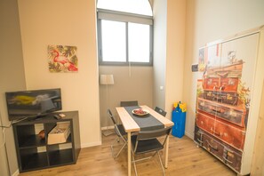 A compact living space with a dining table, chairs, a television, and a wall-mounted cabinet. - Central Station House "Mario", confort and charme!  (Catania)