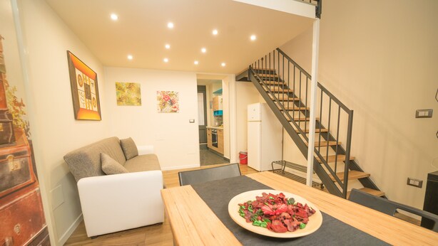 Un salon moderne avec une table à manger en bois, un canapé blanc et un escalier.