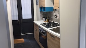 Une cuisine de taille réduite, équipée d’une cuisinière à gaz, d’un évier et de meubles de rangement en bois.