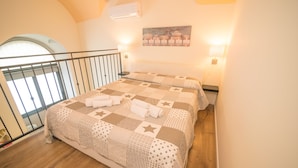 Une chambre avec un grand lit, un balcon et un tableau au mur.