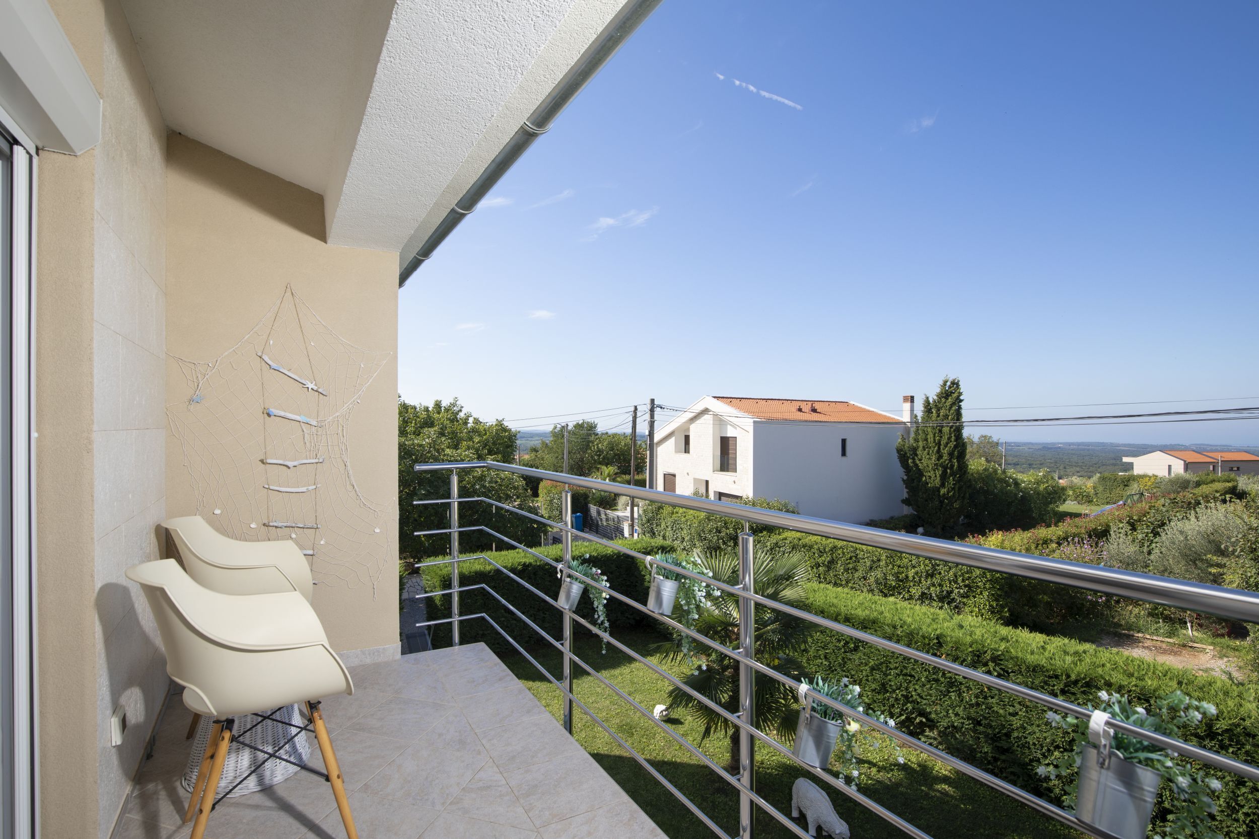 A balcony with a view of a house and garden.