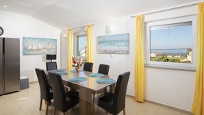 Un comedor con una mesa de madera, sillas negras, cortinas amarillas y dos cuadros en las paredes.