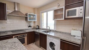 Eine moderne Küche mit Granit Arbeitsplatten, Edelstahlgeräten und Holzschränken.