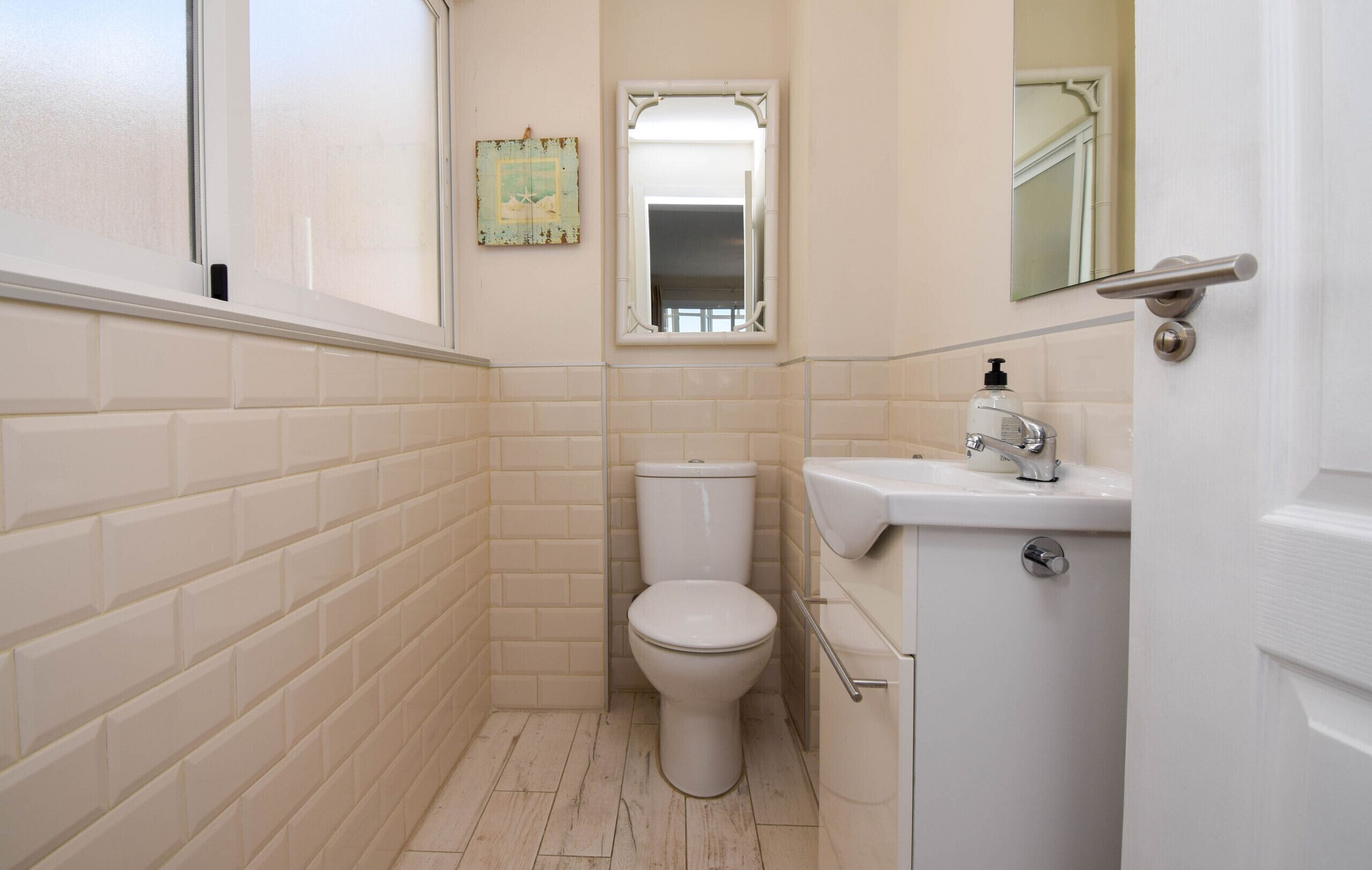 A small, clean bathroom with a toilet, sink, and mirror.