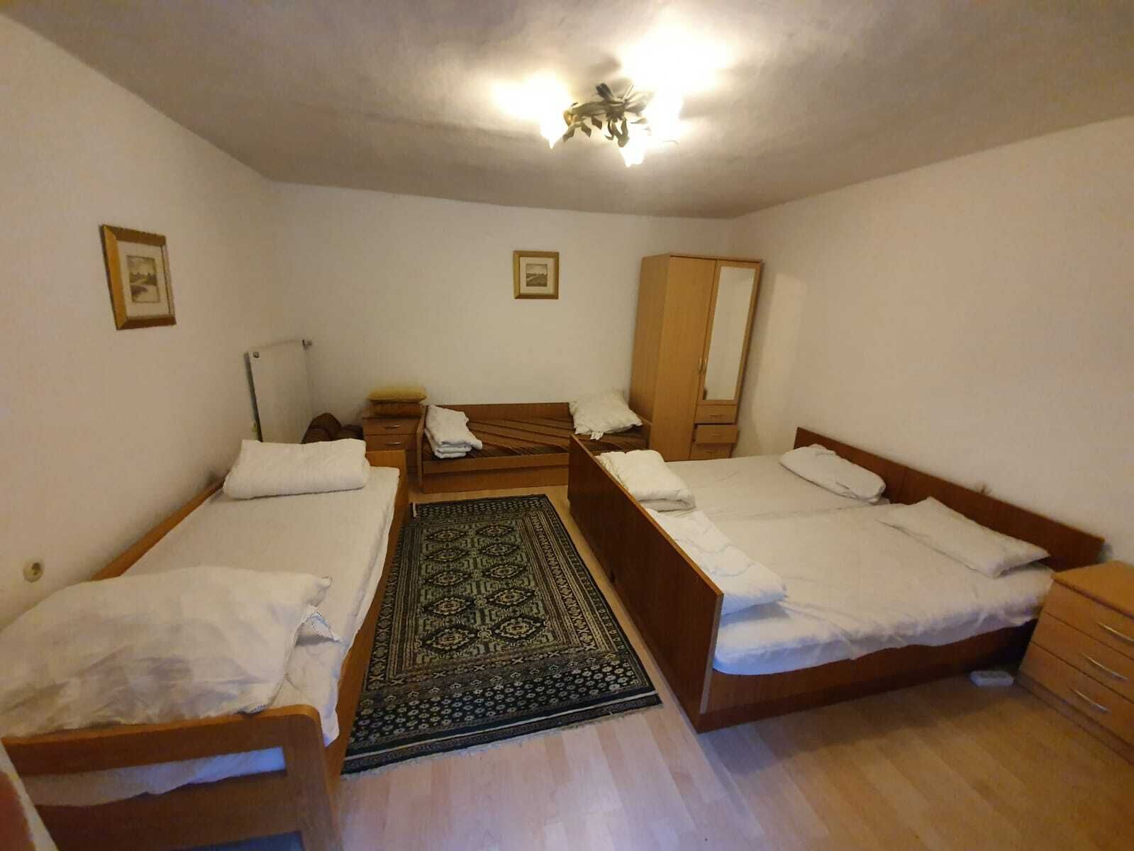 Une chambre avec deux lits simples, une armoire en bois, un miroir et un tapis à motifs.