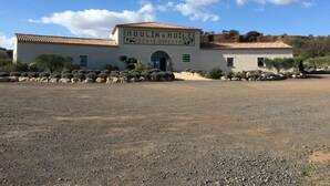 Un edificio con un cartel que dice "Moulin du Mont Ramus" y un estacionamiento de grava frente a él.