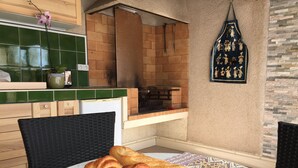 Una cocina con pared de ladrillo, un delantal colgado y una mesa con pan.