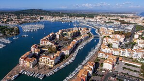 Un puerto deportivo con numerosos barcos amarrados, rodeado de edificios residenciales con tejados de tejas rojas.
