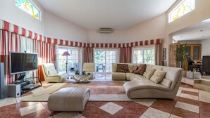 Ein geräumiges Wohnzimmer mit einem großen Ecksofa, einem Fernseher und einem Essbereich mit Tisch und Stühlen.
