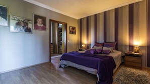 Ein Schlafzimmer mit einem Bett, Nachttischen, Holzboden und einer gestreiften Wand.