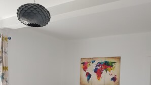 Een moderne woonkamer met een grijze modulaire bank, een wereldkaart schilderij en een bijzondere hanglamp.