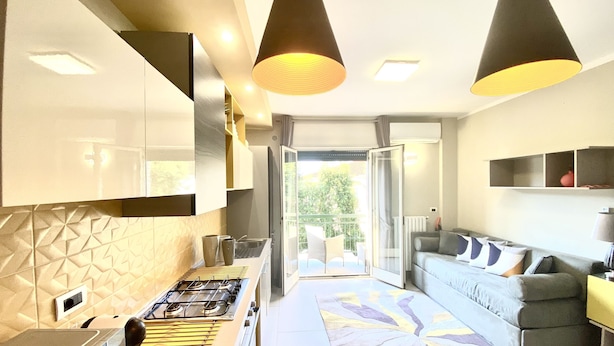 Une cuisine moderne équipée d’une cuisinière à gaz, d’un four à micro-ondes et d’un four encastré. On y trouve également un coin repas avec une table et des chaises, ainsi qu’un salon avec un canapé et une table basse.