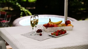 A table with a fruit basket, a plate of strawberries, two glasses of white wine, and a small bowl of cherries.