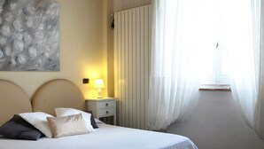 A neatly made bed with a quilted white duvet, a bedside lamp, and a nightstand with a lamp.