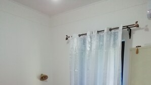 A bedroom with a bed, a curtain, and a wall-mounted heater. - Holiday home Kristin (Lipari)