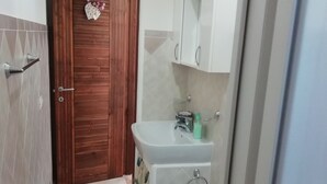 A bathroom with a wooden door, a white sink, a bidet, and a toilet. - Holiday home Kristin (Lipari)