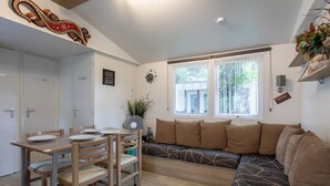 Un salon confortable avec une table à manger, des chaises, un canapé et une fenêtre agrémentée de rideaux.