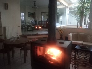 A cozy living room with a fireplace, a dining area, and a sofa.