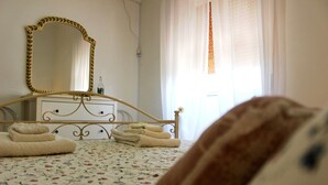 Un dormitorio con cama, cómoda, espejo y ventana con cortinas.