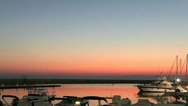 Un puerto deportivo al atardecer con barcos amarrados.