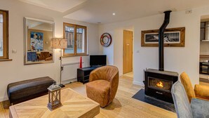 A cozy living room with a fireplace, a dining area with a table and chairs, and a large window.