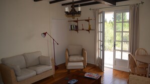 A living room with a sofa, armchair, coffee table, and a dining area with chairs. - The Cottage  near Sainte Foy la Grande (Fougueyrolles)