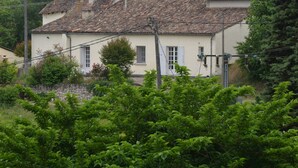 A traditional house with a tiled roof, a stone wall, and lush greenery in the foreground. - The Cottage  near Sainte Foy la Grande (Fougueyrolles)