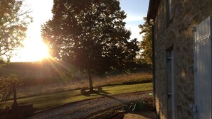 A building with a stone facade, a paved pathway, and a grassy area with a bench. - The Cottage  near Sainte Foy la Grande (Fougueyrolles)
