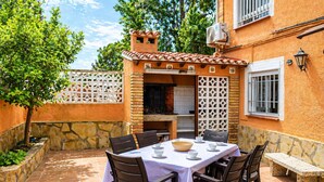 An outdoor patio with a table set for dining, surrounded by stone walls and a brick chimney.